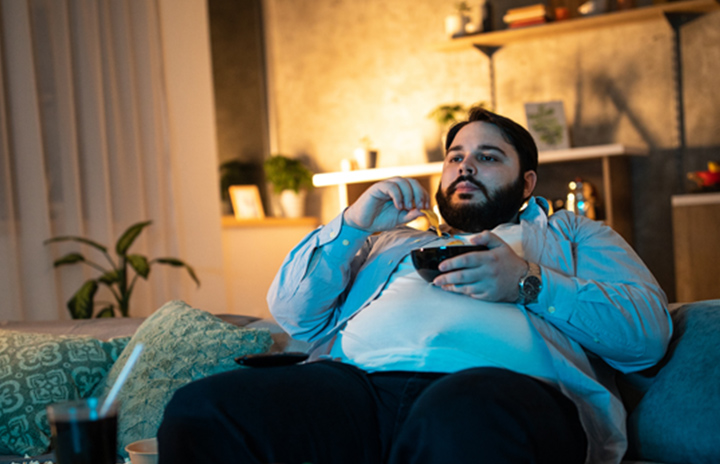 Man sitting on his couch eating chips from a bowl.